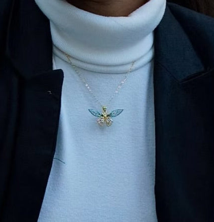 Person wearing a necklace with a detailed pendant on a white turtleneck sweater.