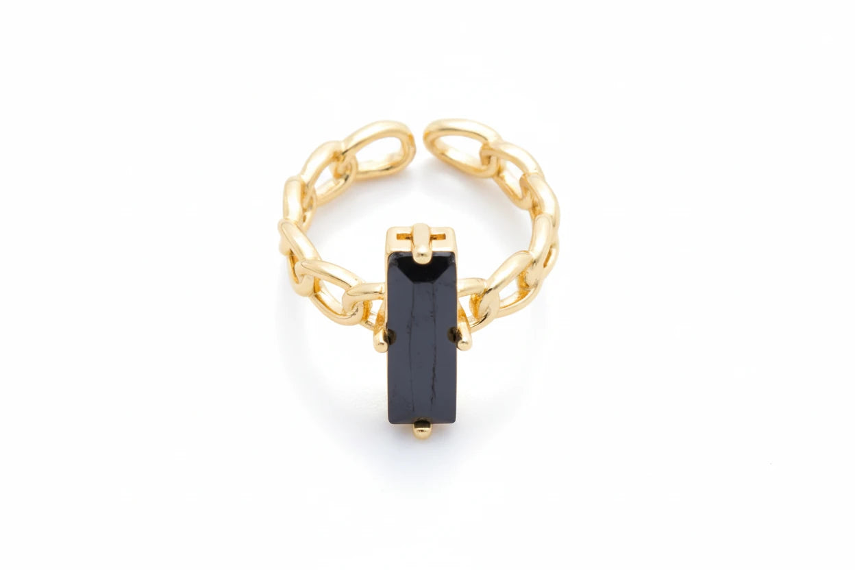 Gold chain ring with a black gemstone on a light gray background