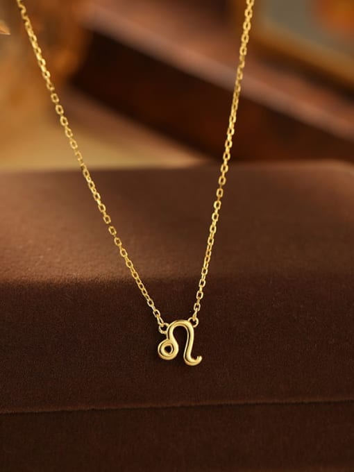 Gold necklace with a zodiac symbol pendant on a brown surface