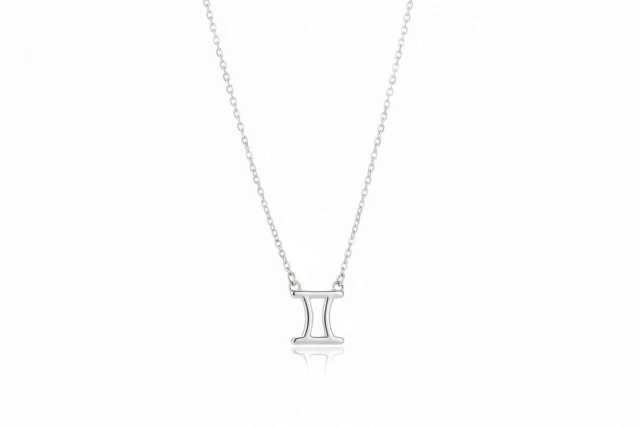 Silver necklace with a gemini zodiac pendant on a white surface