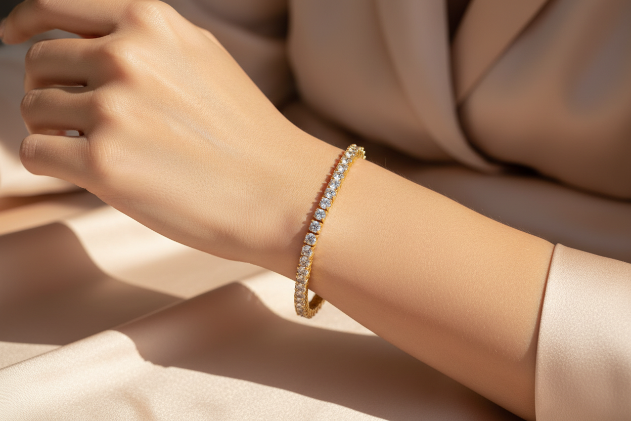 Gold tennis bracelet on a wrist with a neutral background