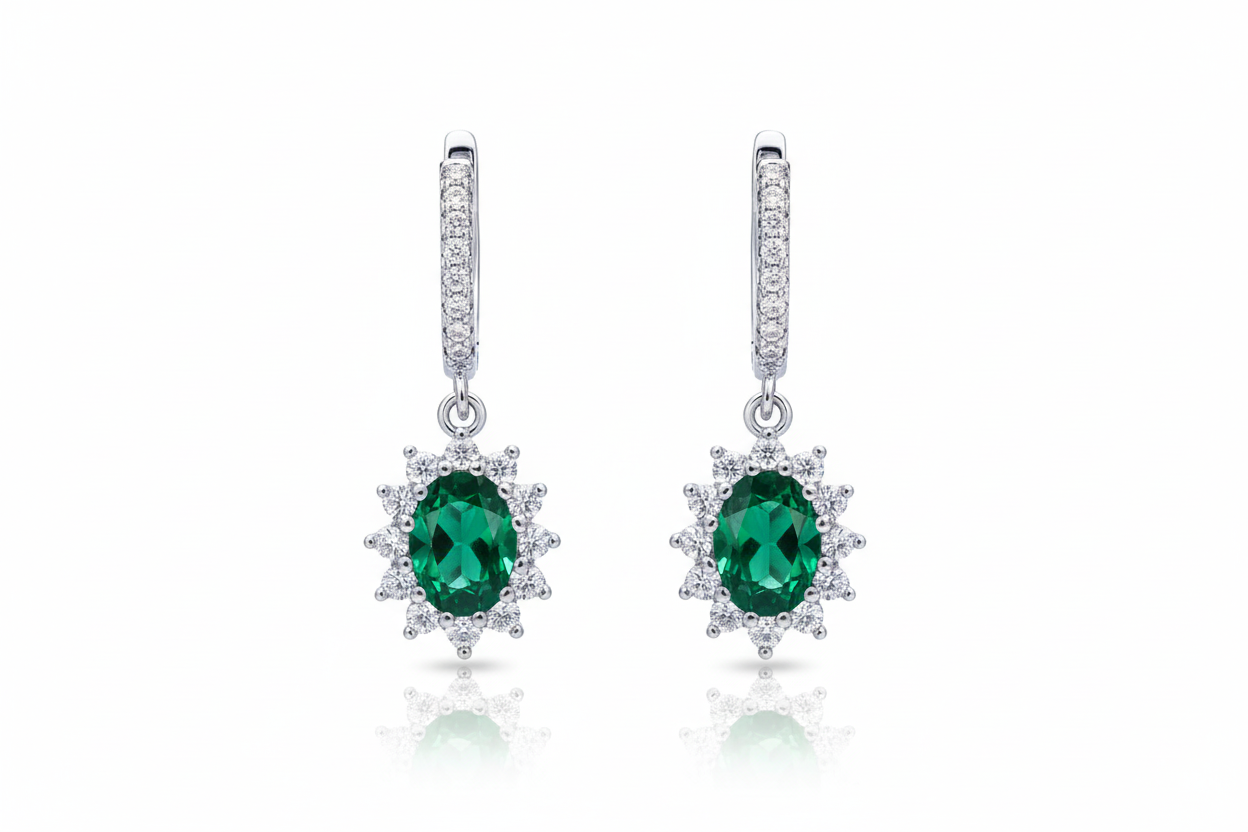 Pair of emerald and diamond earrings on a white background