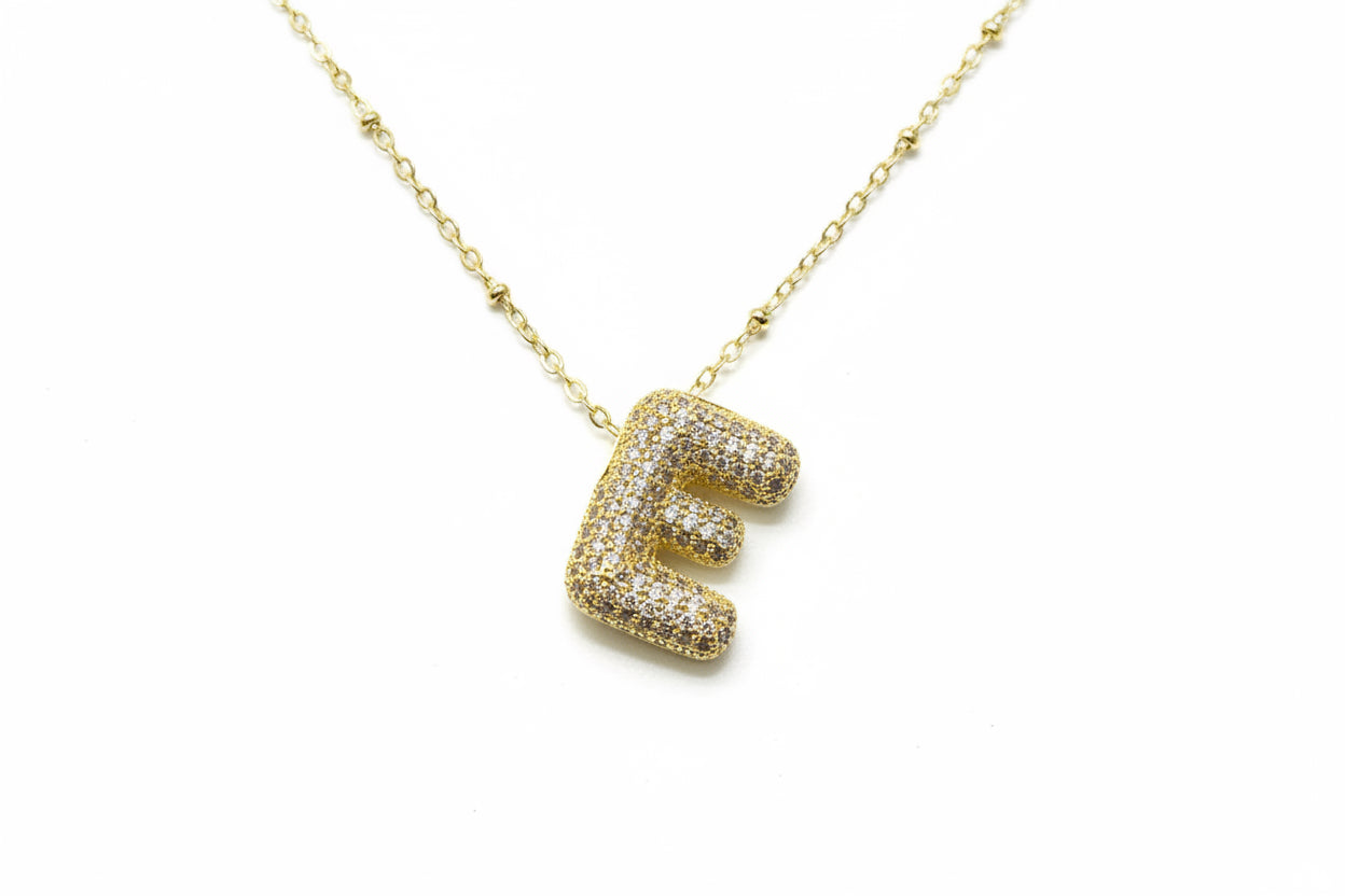 Gold necklace with a 'E' pendant on a white background