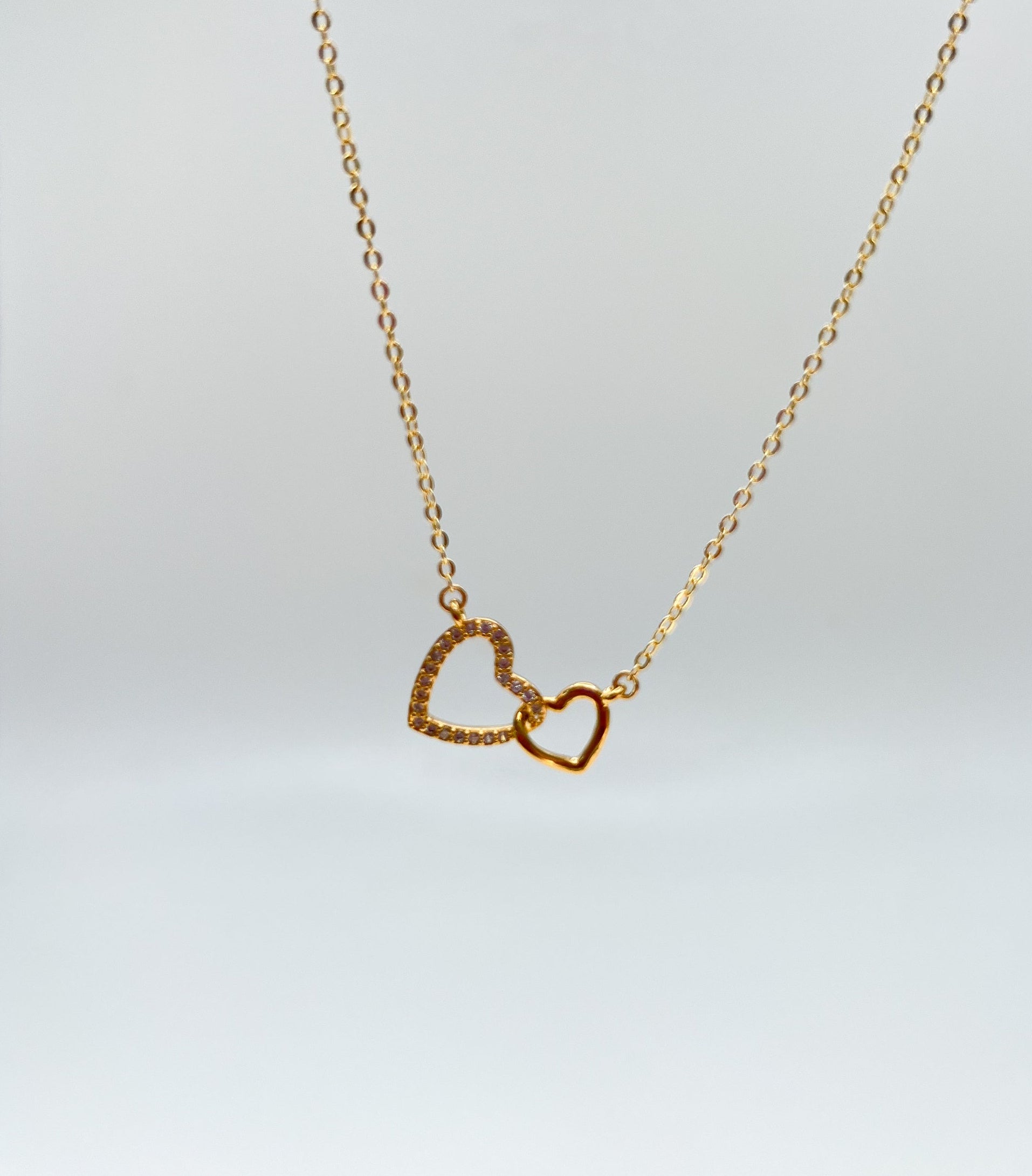 Gold necklace with a heart design on a white background