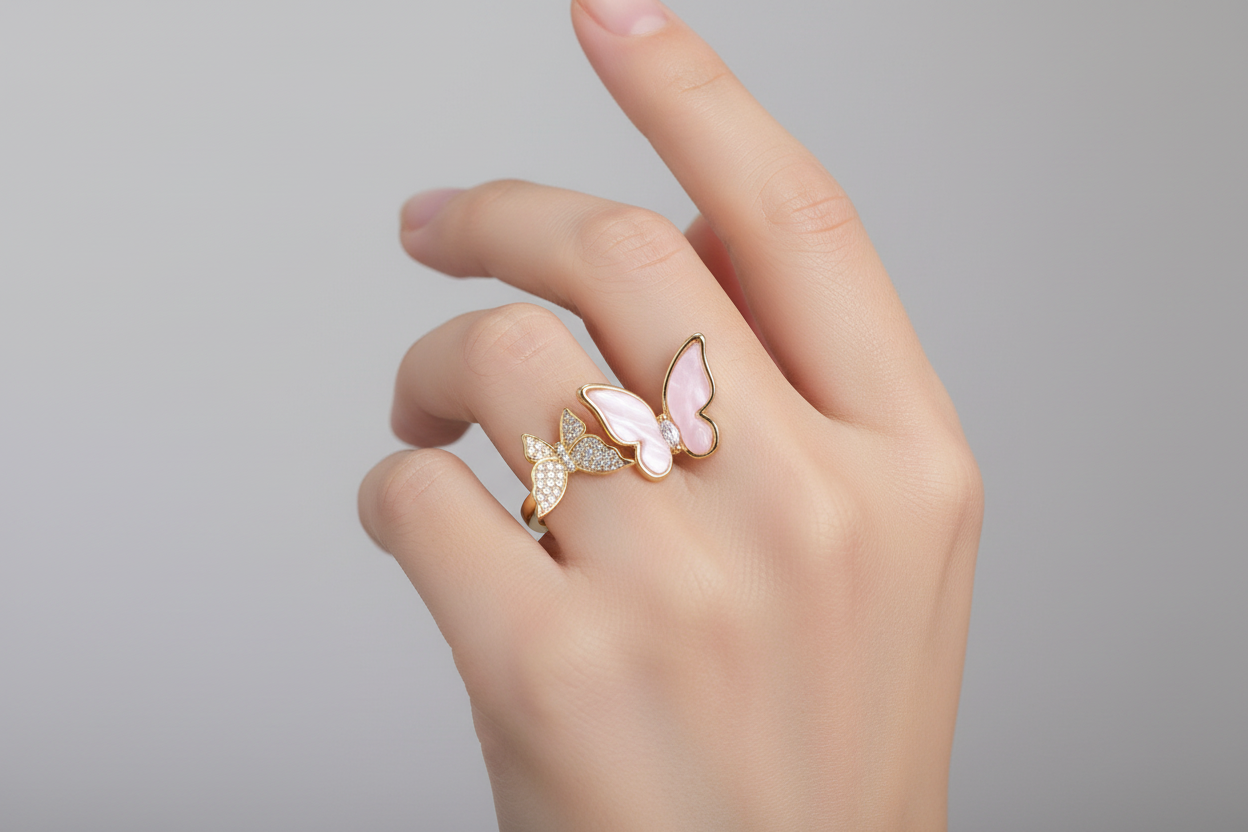 Hand wearing a butterfly-shaped ring on a plain background
