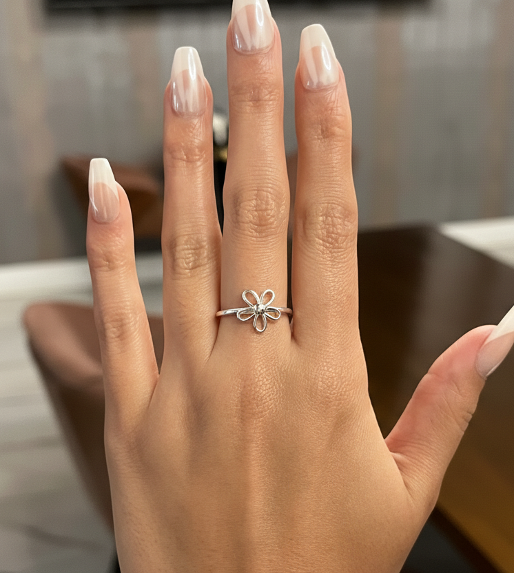 Hand wearing a silver ring with a blurred indoor background