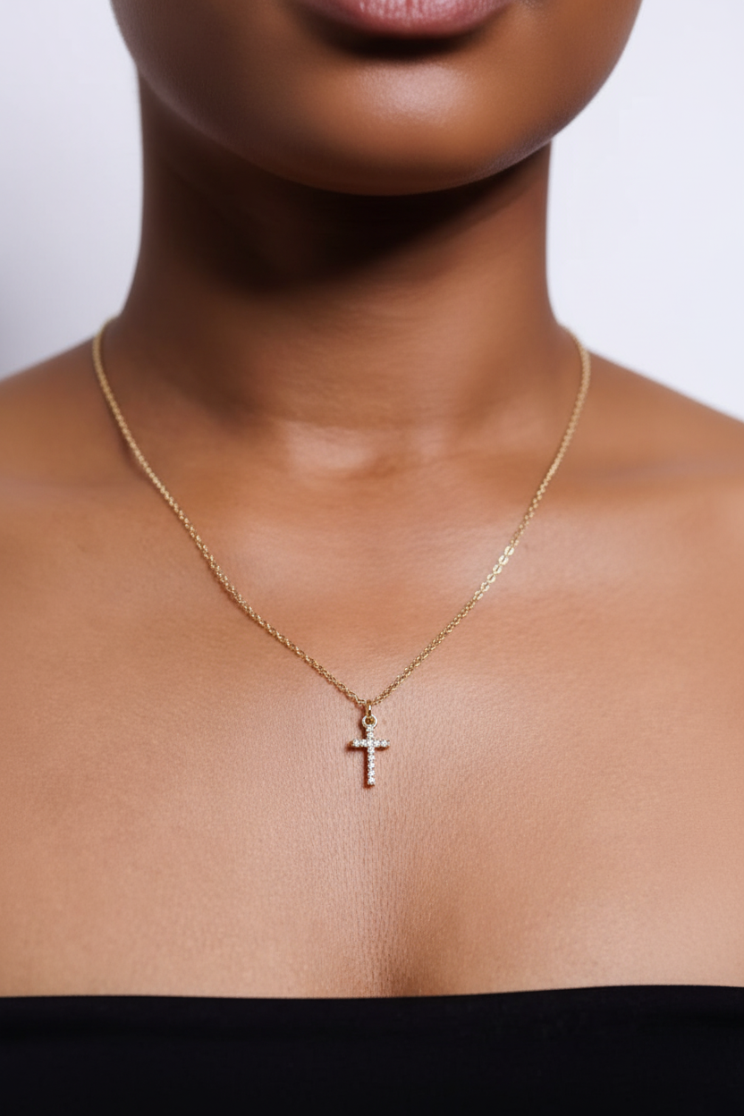 Gold necklace with a cross pendant on a person's neck against a neutral background