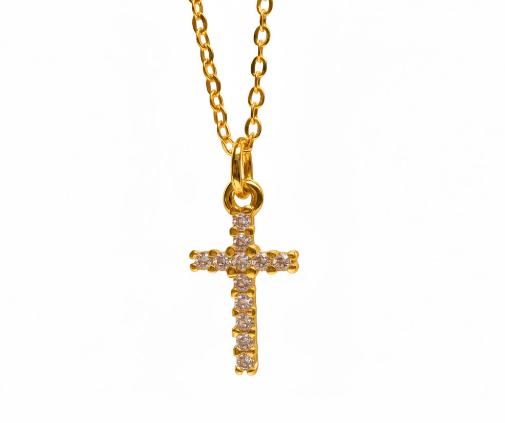 Gold cross necklace with pink gemstones on a white background