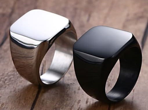 Two rings, one silver and one black, on a wooden surface.