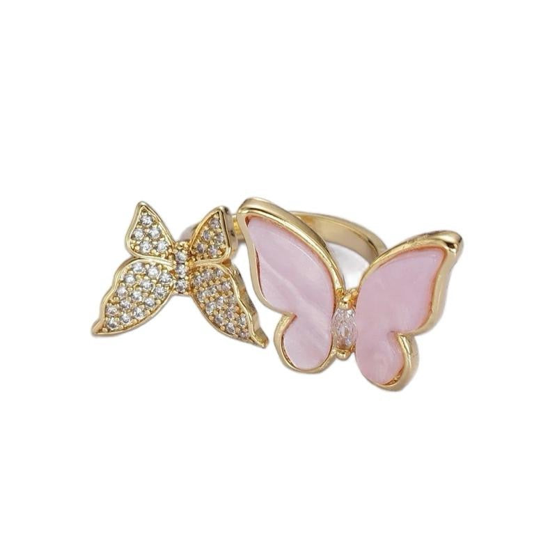 Butterfly-shaped ring with gold and pink design on a white background