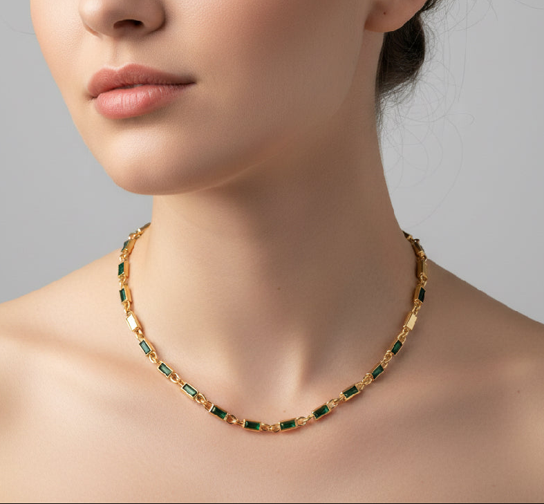 Gold necklace with green gemstones on a plain background
