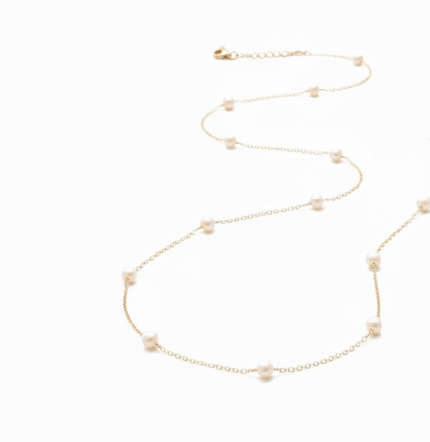 Delicate gold necklace with small beads on a white background