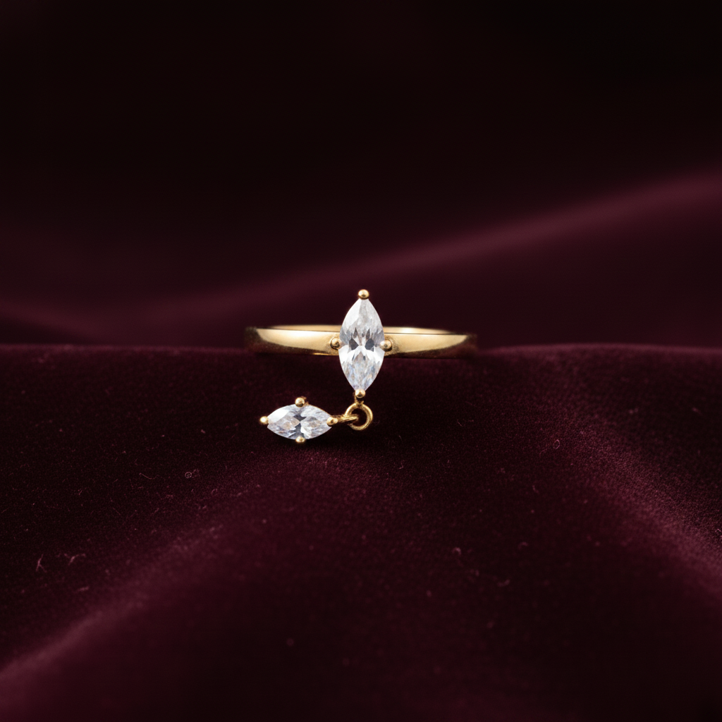 A gold ring with marquise-cut clear gemstones, displayed on a dark burgundy velvet fabric background.