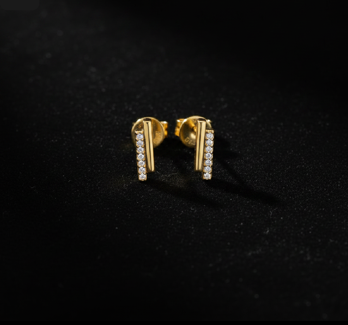 Gold earrings with clear stones on a black background