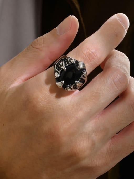 Close-up of a hand wearing a decorative ring with a black gemstone.