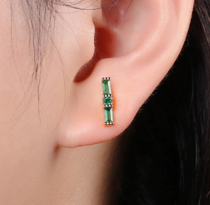 Close-up of an ear wearing a green gemstone earring.