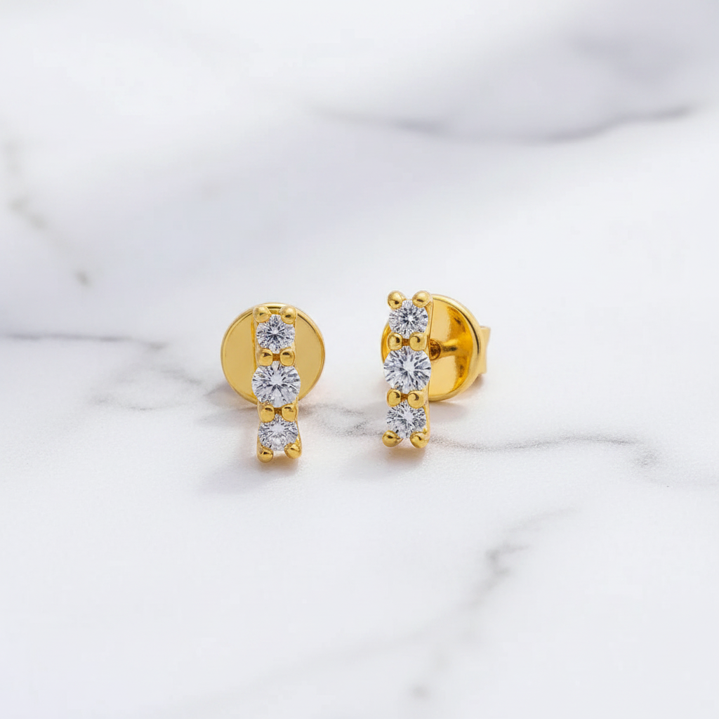 Gold earrings with clear gemstones on a marble surface