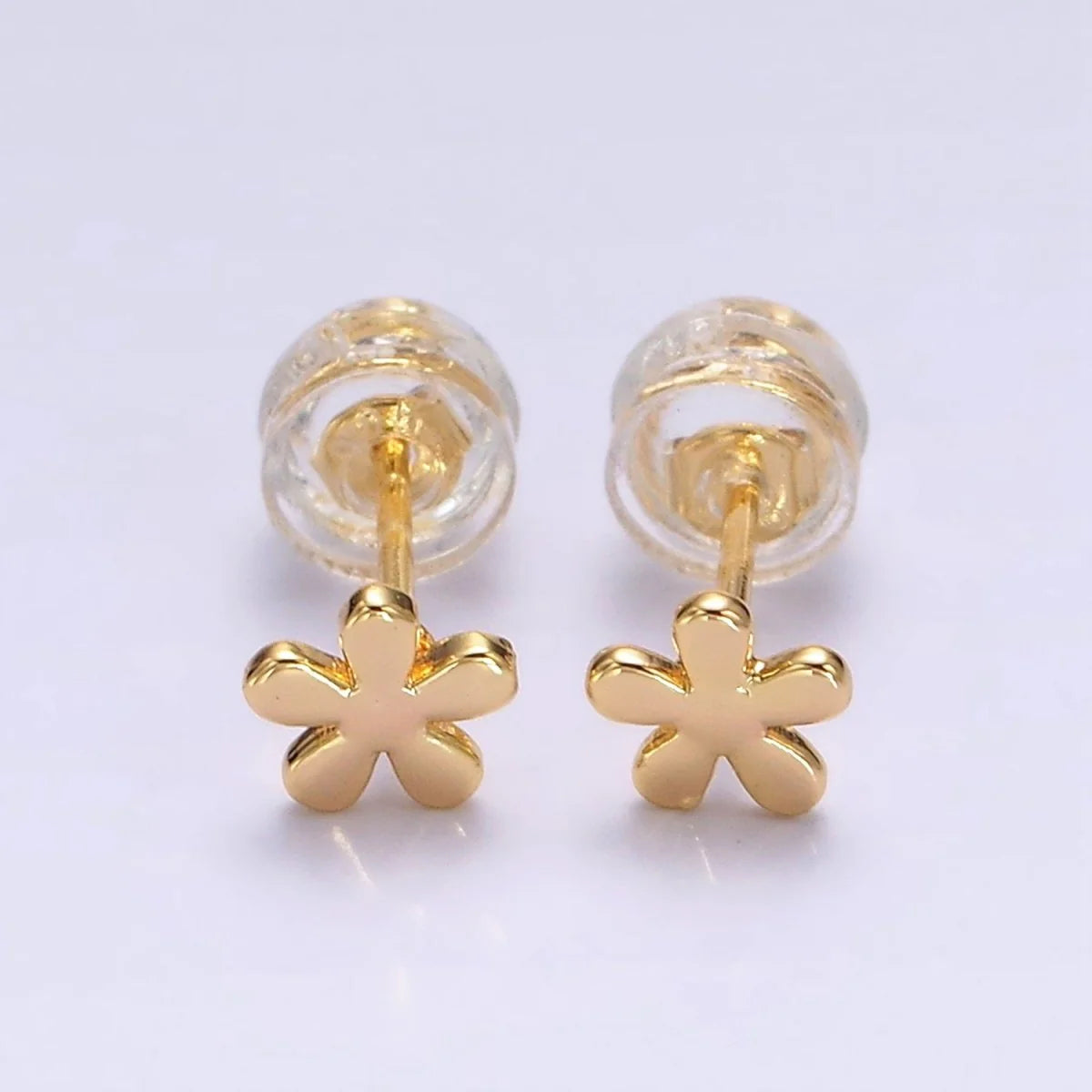 Gold flower-shaped earrings on a light purple background