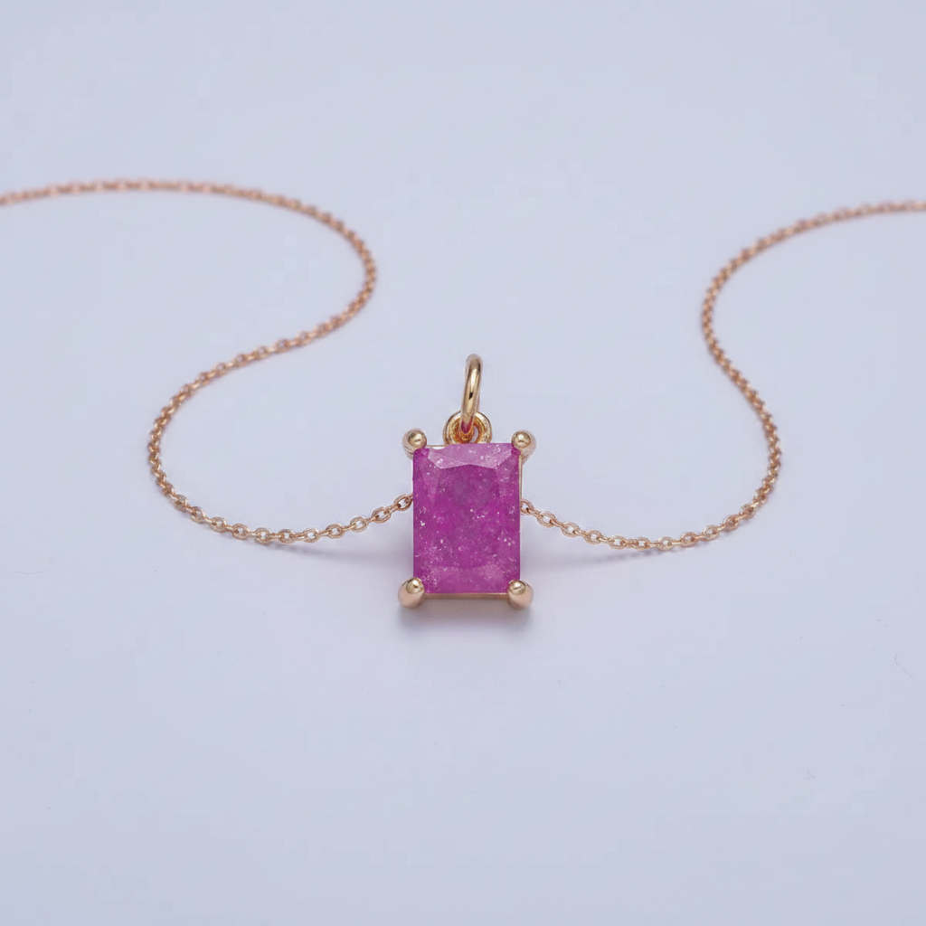 Pink gemstone pendant on a gold chain against a light gray background