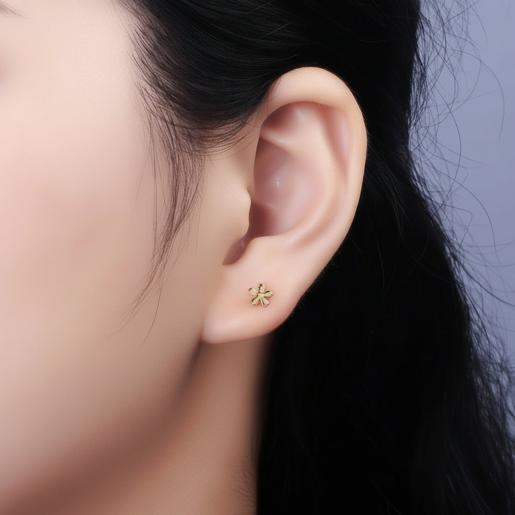 Close-up of an ear wearing a gold stud earring with a dark background