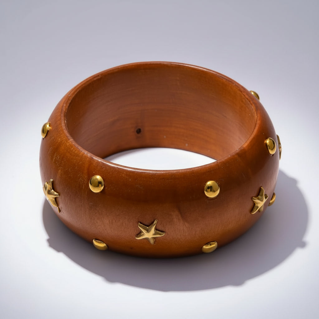 Brown wooden bangle with gold studs on a white background