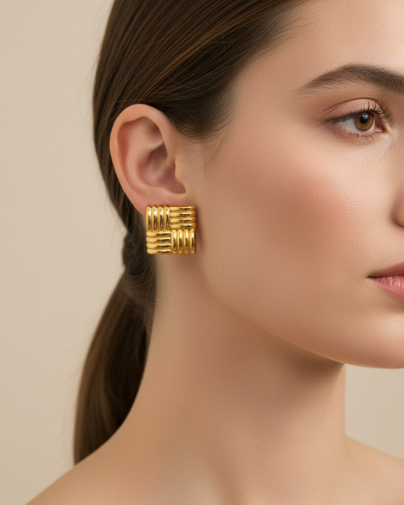 Gold hoop earrings worn by a model against a neutral background