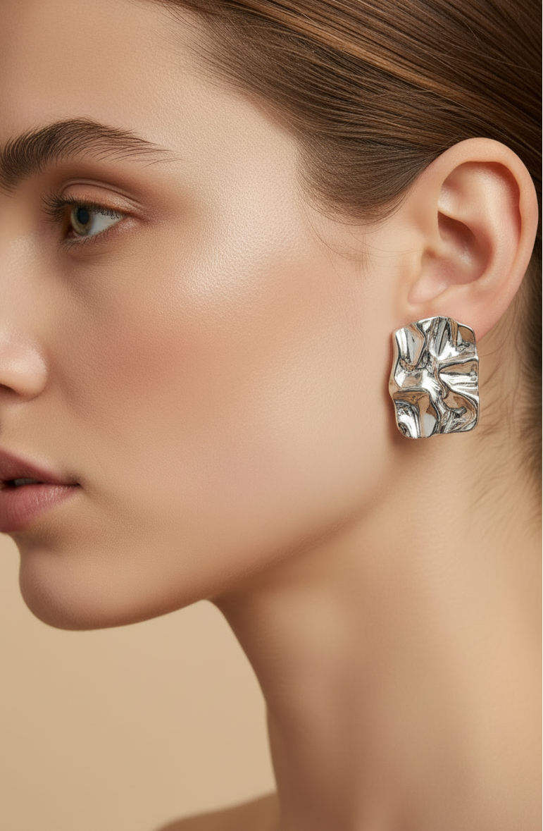 Close-up of a woman wearing a silver earring against a neutral background