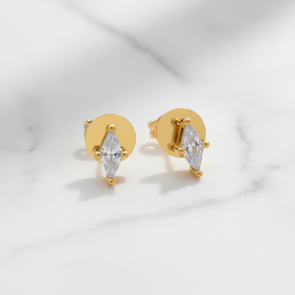 Gold earrings with clear gemstones on a light gray background