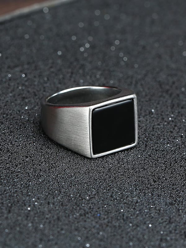 Silver ring with a black stone on a textured black surface