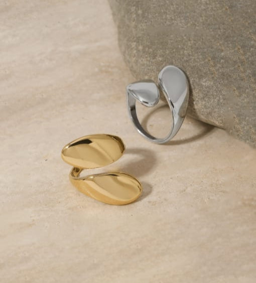 Gold and silver open ring on a textured beige surface