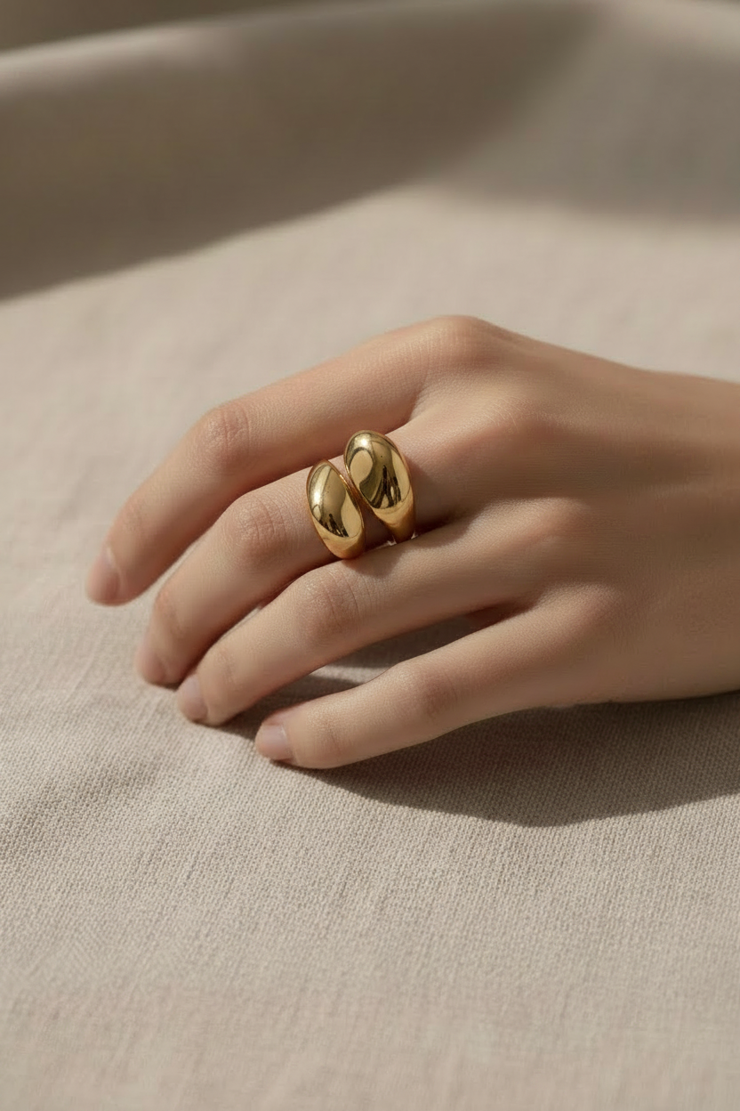 Gold ring on a hand against a beige background