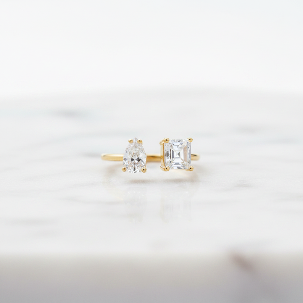 Gold earrings with clear gemstones on a light gray background