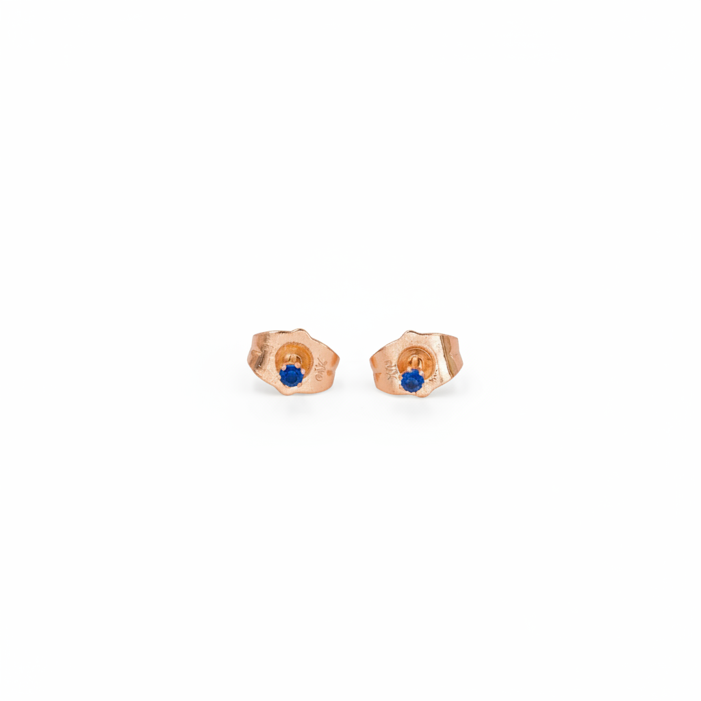 Pair of rose gold earrings with blue gemstones on a white background