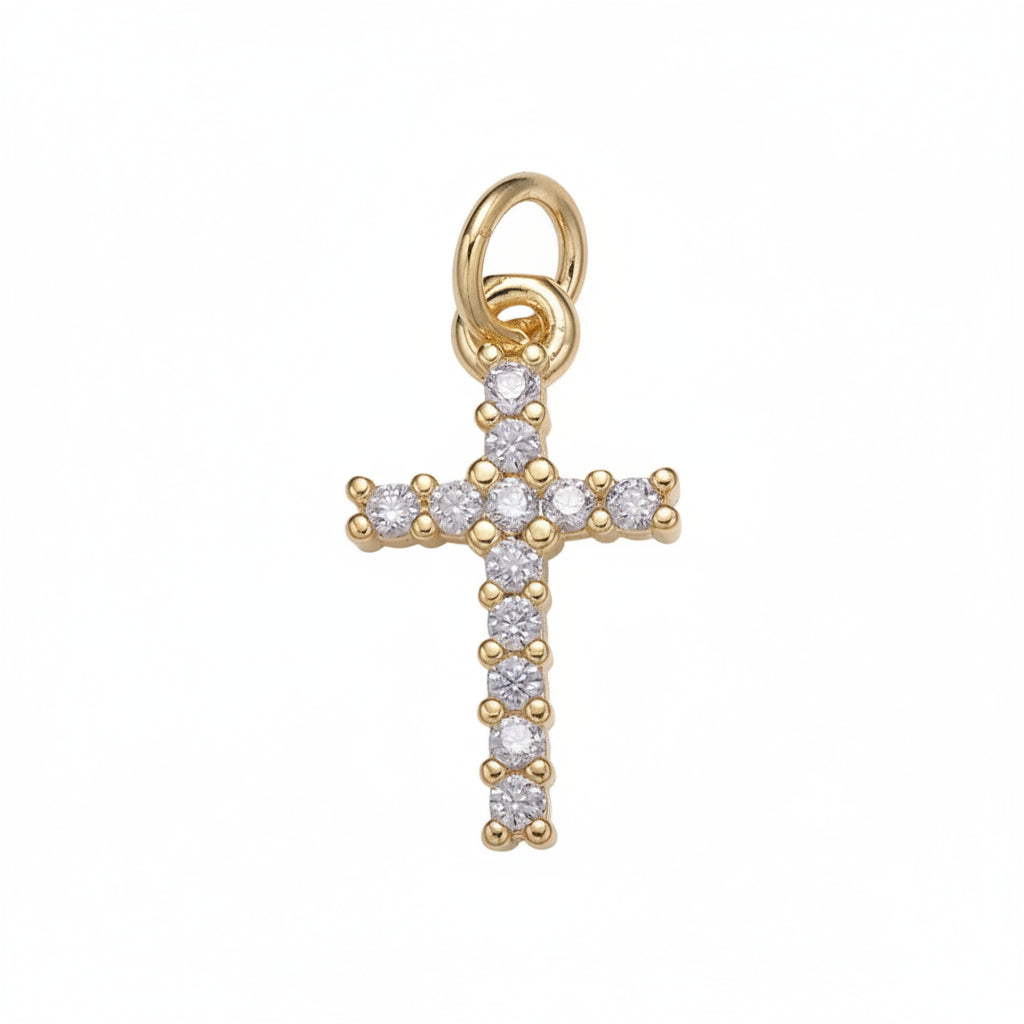 A gold cross pendant adorned with small clear gemstones, set against a plain light gray background.