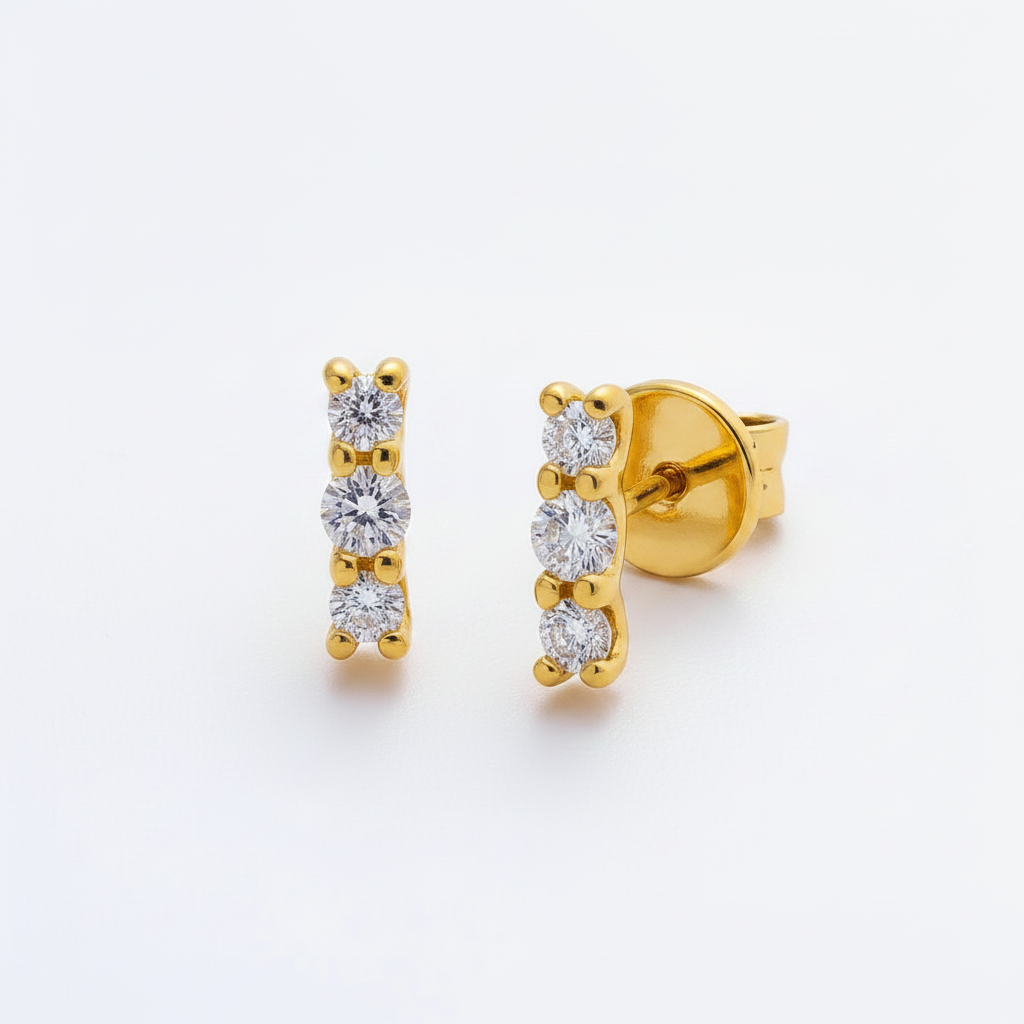 Gold earrings with clear gemstones on a white background