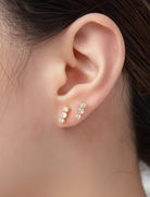 Close-up of an ear wearing gold and diamond earrings with a blurred background