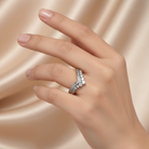 Hand wearing a diamond ring on a beige fabric background