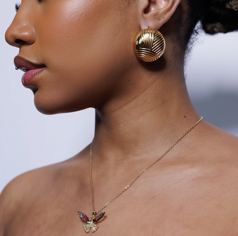 Woman wearing gold earrings and necklace against a light gray background