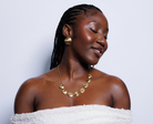 Woman wearing gold jewelry against a light gray background