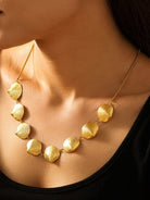 Gold necklace with shell-shaped pendants on a person wearing a black top.