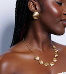 Woman wearing gold jewelry against a light background