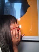 Woman with red nails wearing a clear 3-stone diamond ring 