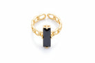 Gold chain ring with a black gemstone on a light gray background