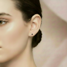 Close-up of a woman's ear wearing a black earring against a blurred background