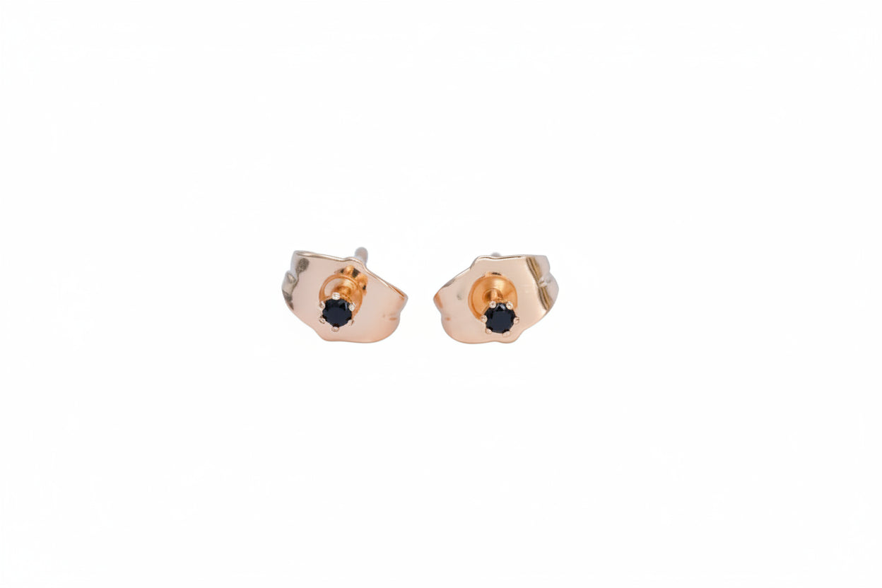 Rose gold earrings with black gemstones on a light blue background