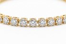 Gold bracelet with clear gemstones on a white background