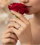 Person holding a red rose wearing a ring on a blurred background