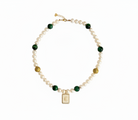 Gold necklace with green stones on a white background
