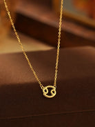 Gold necklace with a zodiac symbol pendant on a brown surface