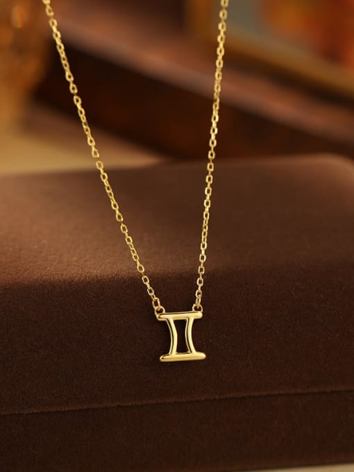 Gold necklace with a Gemini symbol pendant on a brown surface